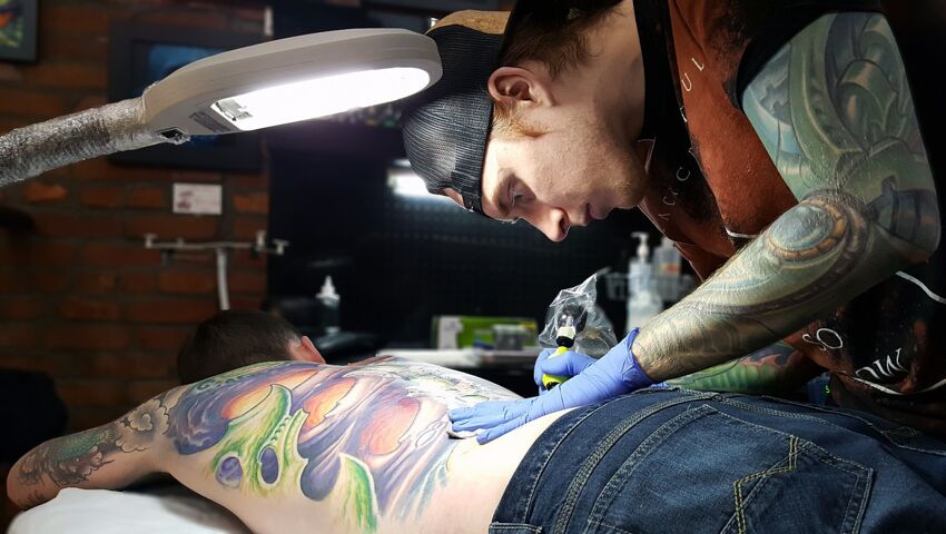 robienie kolorowego tatuażu na plecach