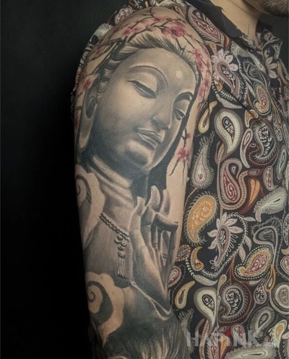 Tattoo Budda in religious motif and realistic style on the upper arm