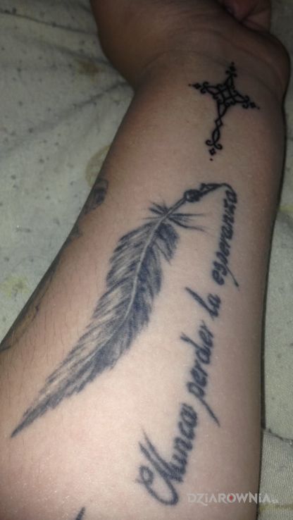 Tatuaż piorko z cytatem po hiszpansku w motywie napisy na przedramieniu