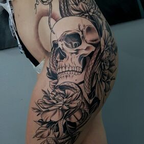 Tatuaż Czaszka z wężem na udzie motyw: czarno-szare styl: graficzne / ilustracyjne