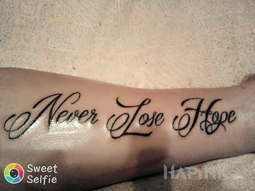Tattoo Nigdy nie trać nadzieji in lettering motif on the forearm
