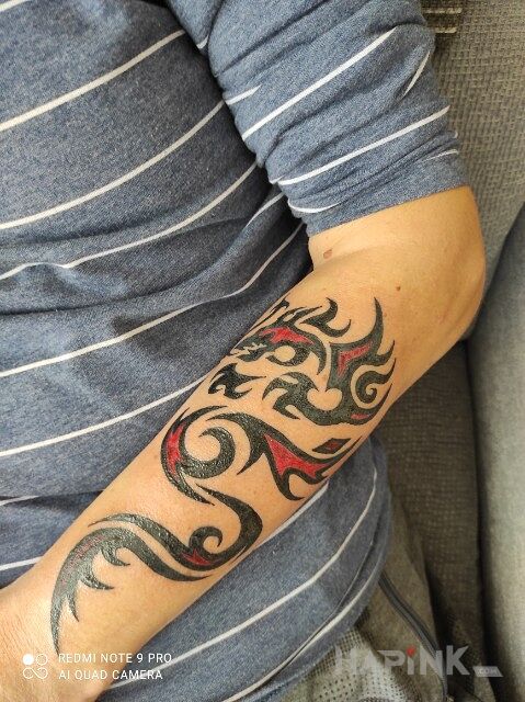 Tattoo Scorpion in colorful motif and tribal style on the forearm