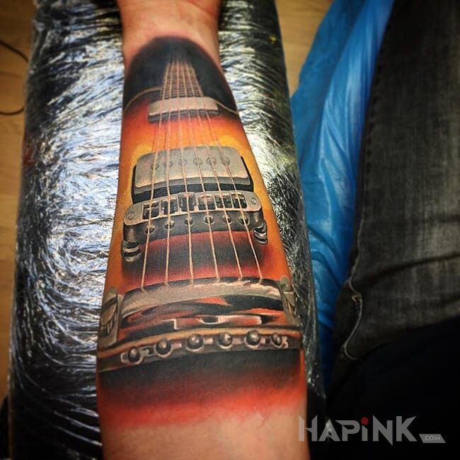 Tattoo Gitara in colorful motif and realistic style on the forearm