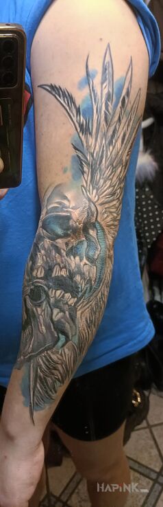 Tattoo Czaszka in wings motif and graphic / illustrative style On the arm