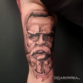 Tatuaż Pilsudzki na bicepsie motyw: czarno-szare styl: graficzne / ilustracyjne