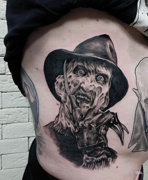 Tattoo Freddy in faces motif and realistic style on the ribs