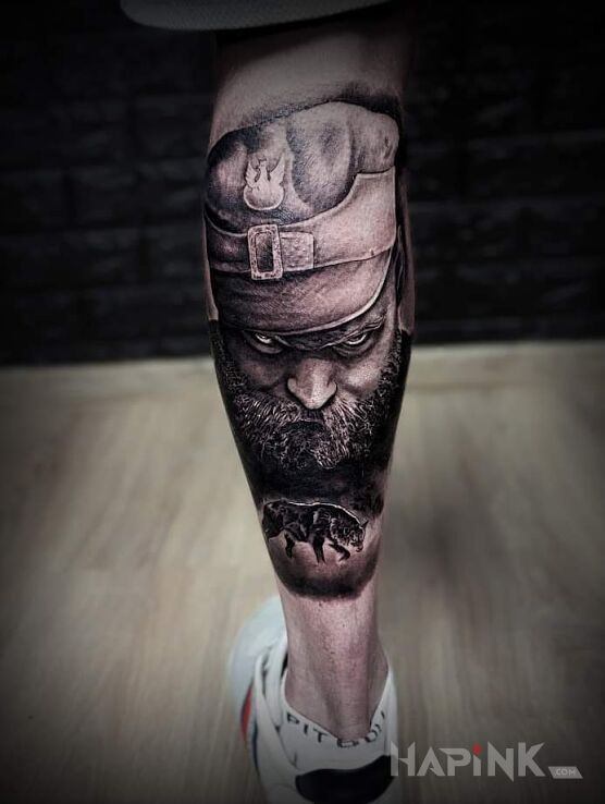Tattoo Hubal in faces motif and realistic style on the calf