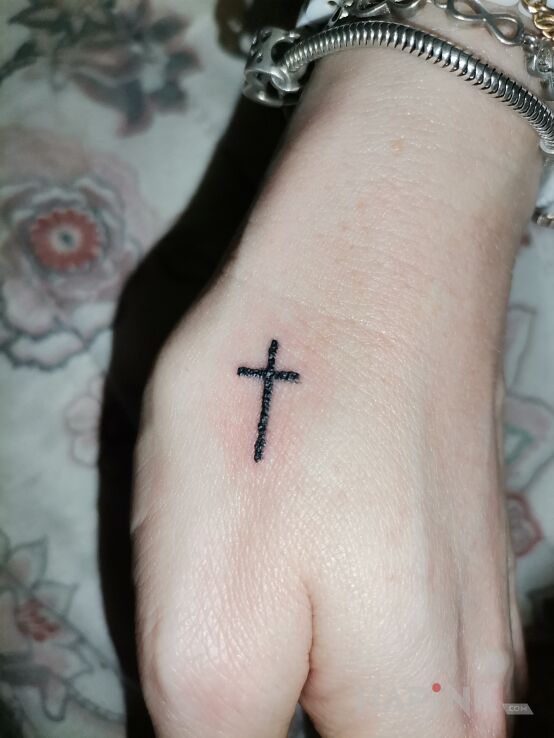 Tattoo Krzyzyk in black and gray motif and minimalistic style on the hand