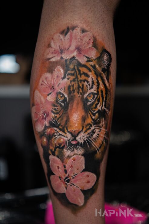 Tattoo Tygrys in flowers motif and realistic style on the calf