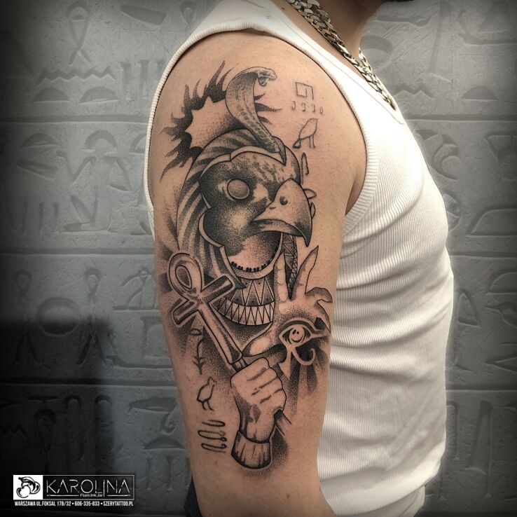 Tatuaż egipski bóg ra w motywie ornamenty i stylu kreskówkowe / komiksowe na ramieniu