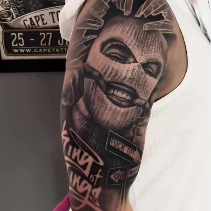 Tatuaż kominiarka w motywie napisy i stylu realistyczne na bicepsie