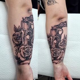 Tattoo Roses and revolver On the arm motif: flowers style: realistic