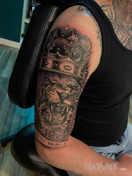 Tattoo Lew w koronie in objects motif and realistic style on the upper arm