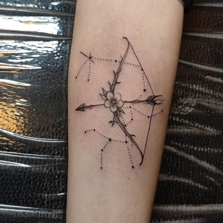 Tatuaż  na przedramieniu strzelec łuk z kwiatem w motywie kosmos i stylu szkic na przedramieniu