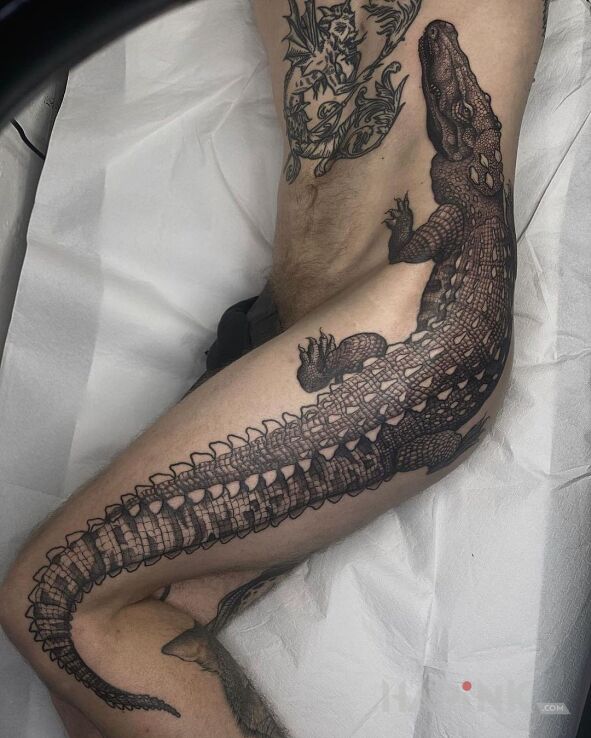 Tattoo Lacoste in black and gray motif and realistic style on the thigh