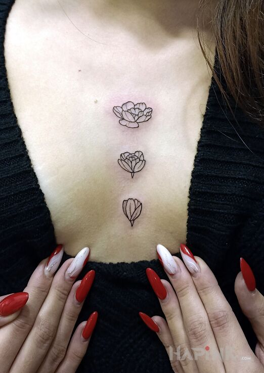 Tattoo Flower tattoo between the breasts in flowers motif and contour / linework style on the chest