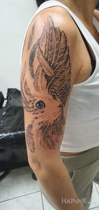 Tattoo Kot in wings motif and realistic style on the upper arm