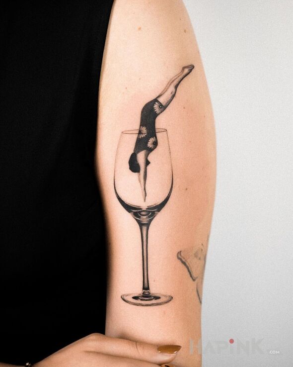 Tattoo Skok do kieliszka in black and gray motif and realistic style on the upper arm
