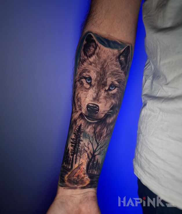 Tattoo Wilk a pod nim ognisko w lesie in animals motif and realistic style on the forearm