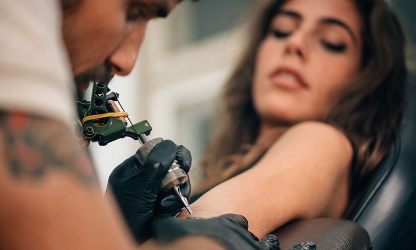 tatuażysta tatuujący rękę dziewczynie