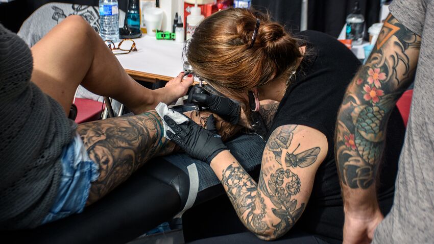 tatuażystka robiąca tatuaż na nodze