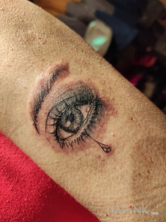 Tattoo Oko łza in black and gray motif and realistic style on the upper arm