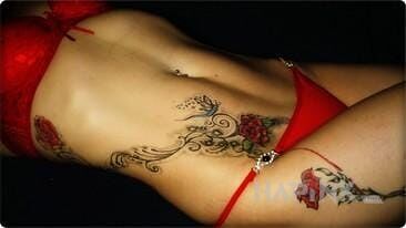 Tattoo Na czerwono in flowers motif on the ribs