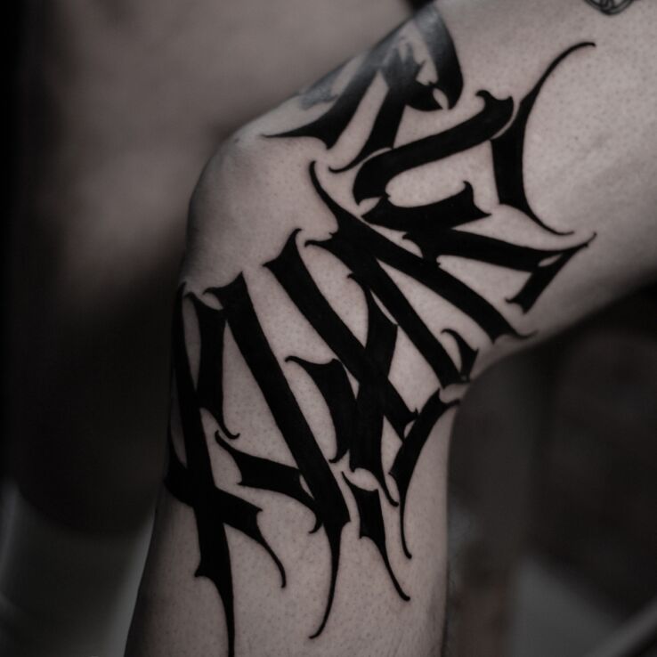 Tattoo Black calligraphy around the knee in criminal lettering motif and calligraphy style on the knee