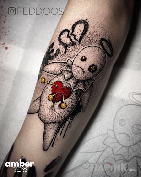 Tattoo Laleczka Voodoo in dark motif and graphic / illustrative style On the arm