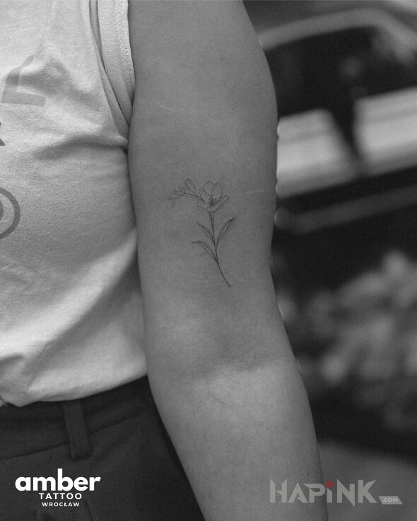 Tattoo Kwiatuszek in black and gray motif and minimalistic style on the bicep