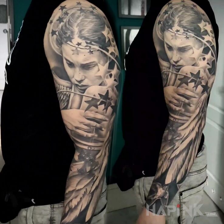 Tattoo Anioł z głową w gwiazdach in faces motif and realistic style on the upper arm