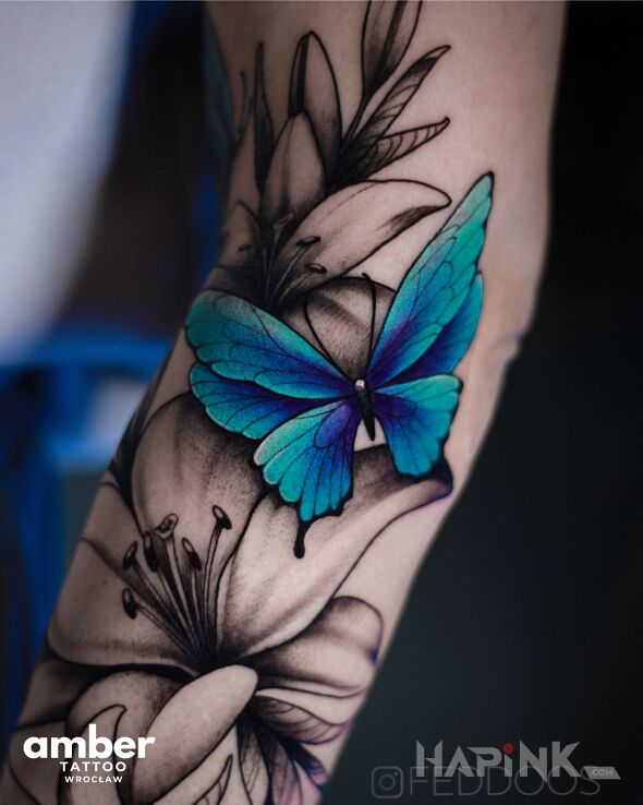 Tattoo Błękitny motyl in flowers motif and realistic style On the arm