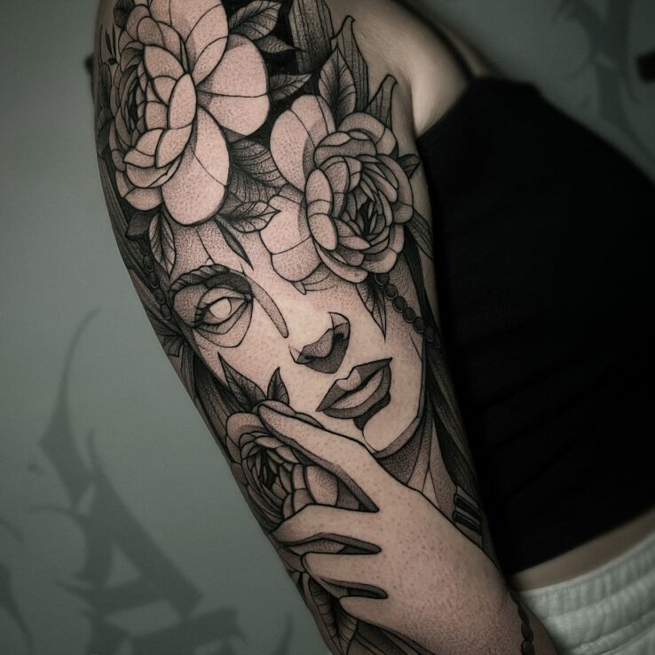 Tattoo Face in Flowers in black and gray motif and graphic / illustrative style On the arm