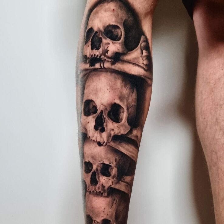 Tattoo Pile of skulls in black and gray motif and realistic style on the leg