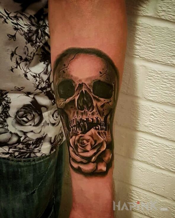 Tattoo Tatto skull in flowers motif on the forearm