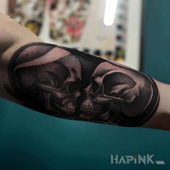 Tattoo Czaszki in skulls motif and realistic style on the bicep