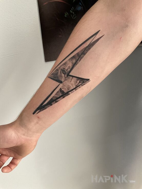Tattoo Lew w piorunie in black and gray motif and graphic / illustrative style On the arm