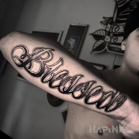 Tattoo Blessed. On the arm motif: criminal lettering style: calligraphy