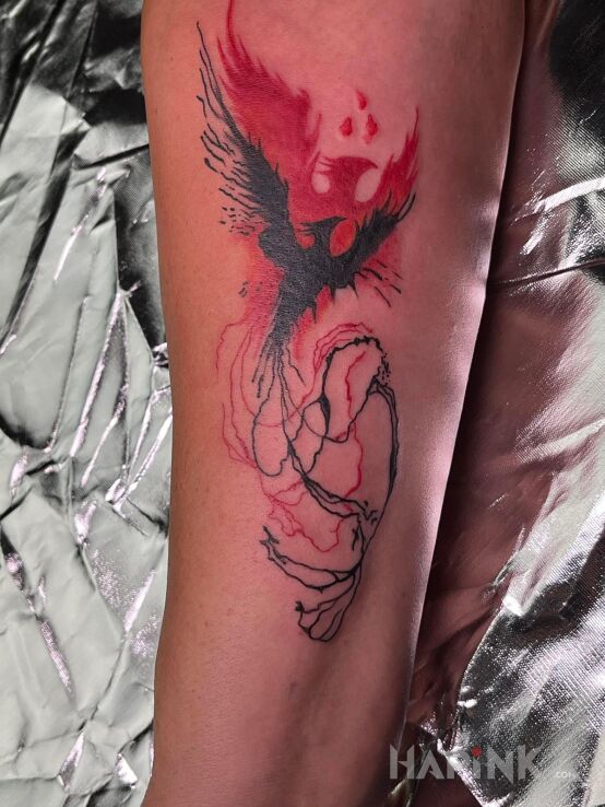 Tattoo Feniks - Nowy początek in wings motif and trash polka style on the forearm