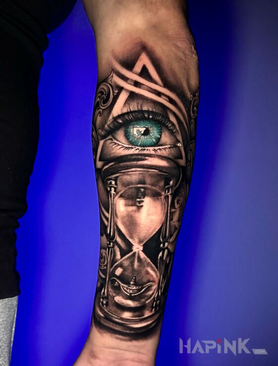 Tattoo Oko i klepsydra na przedramieniu in objects motif and realistic style on the forearm