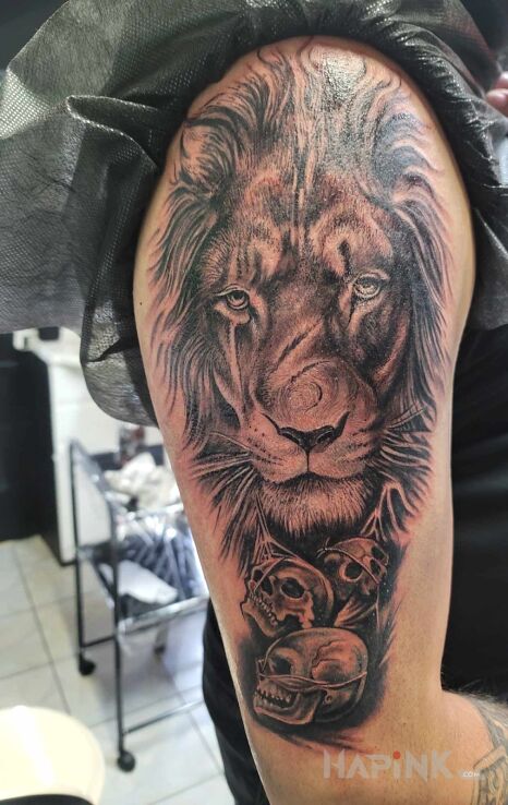 Tattoo Lew Czaszki in dark motif and realistic style on the shoulder