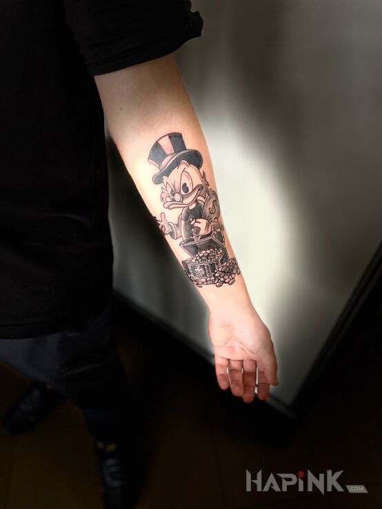 Tattoo SCROOGE MC DUCK in black and gray motif and graphic / illustrative style on the forearm