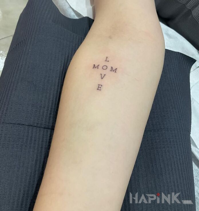 Tattoo Love Mom in lettering motif and calligraphy style on the forearm