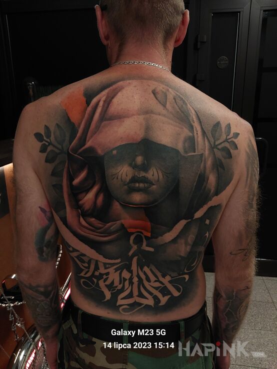 Tattoo Asasin w wersji damskiej in criminal lettering motif and realistic style on the shoulder blades