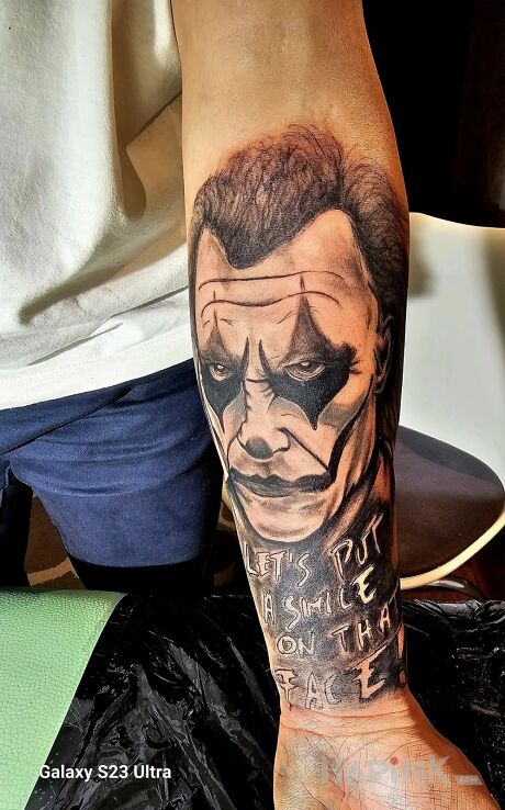 Tattoo Joker in faces motif and realistic style On the arm