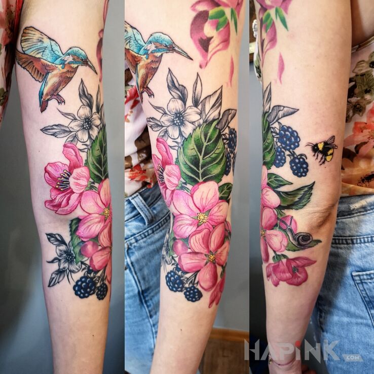 Tattoo Koliber nad kwiatami in floral motif and realistic style on the upper arm