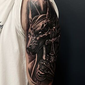 Tattoo Egyptian deity Anubis On the arm motif: black and gray style: realistic