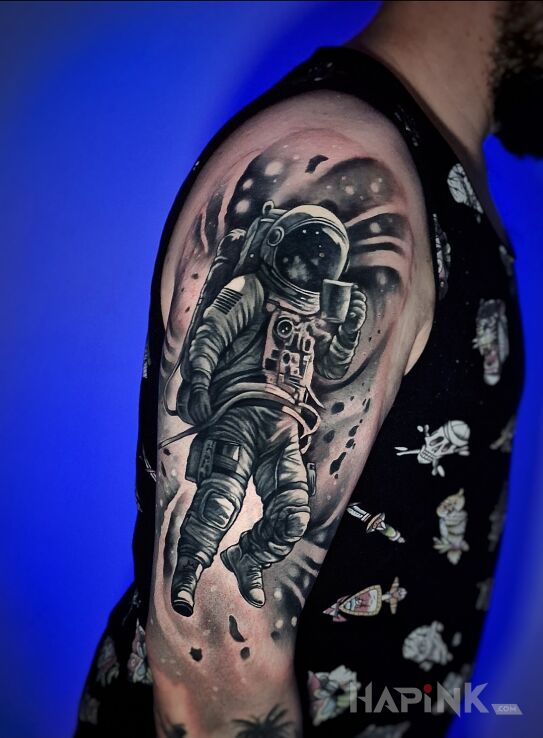 Tattoo Kosmonauta z kubkiem in cosmos motif and realistic style on the upper arm