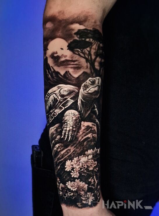 Tattoo Zółw na kamieniu in flowers motif and realistic style on the forearm