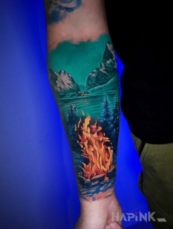 Tattoo Ognisko las i jezioro in nature motif and realistic style on the forearm
